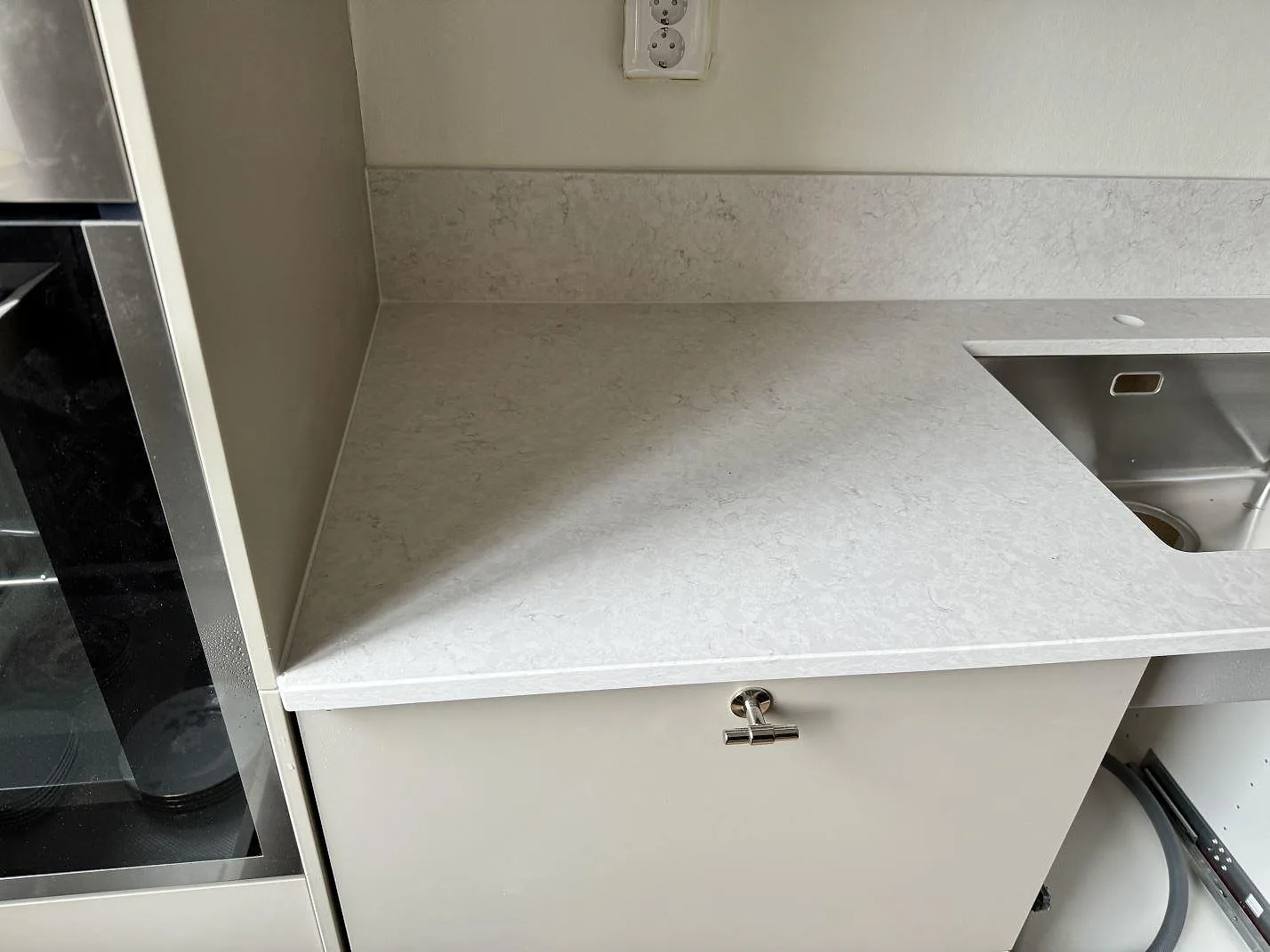 Rak köksbänkskiva i polerad Silestone Snowy Ibiza med rostfri diskho, ljus ådring och vit skåpsrad i Malmö.