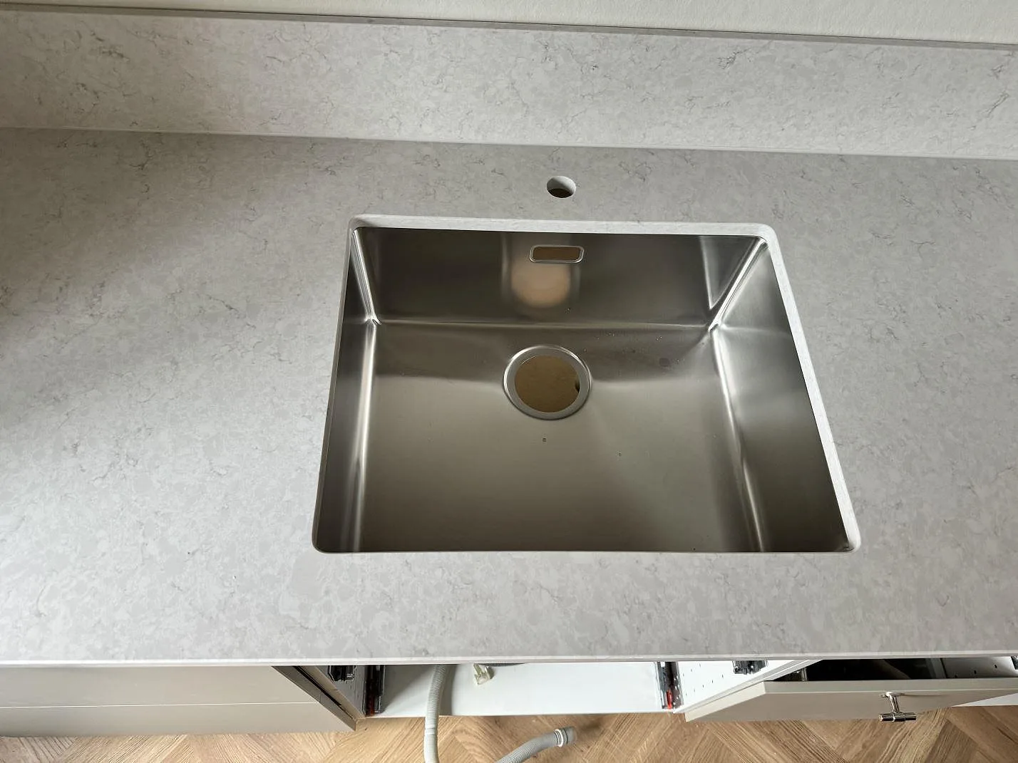 Närbild på underlimmad rostfri diskho i en polerad Silestone Snowy Ibiza bänkskiva med matchande stänkskydd i Malmö.