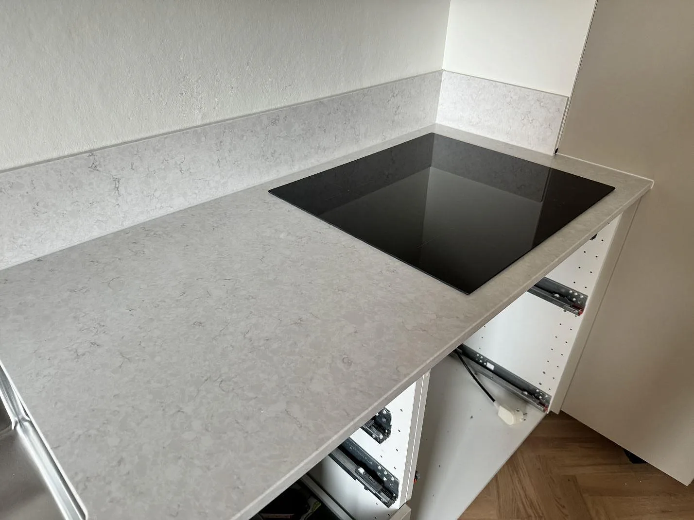 Polerad Silestone Snowy Ibiza som köksbänkskiva runt en svart häll, med ljus ådring och vita köksstommar i Malmö.