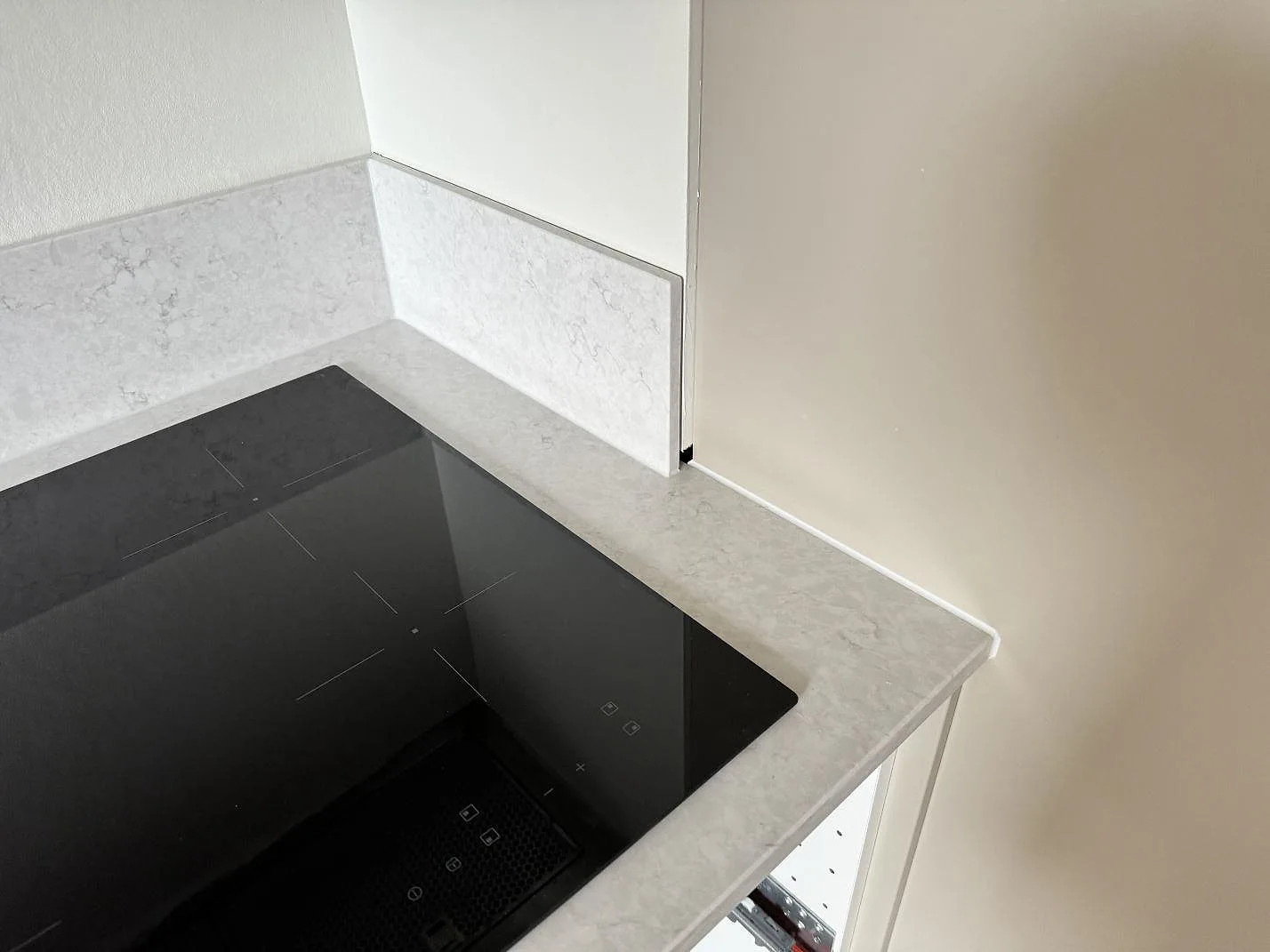Detalj av hörnet vid hällen med polerad Silestone Snowy Ibiza, ljus bänkskiva och uppvikt stänkskydd i Malmö.