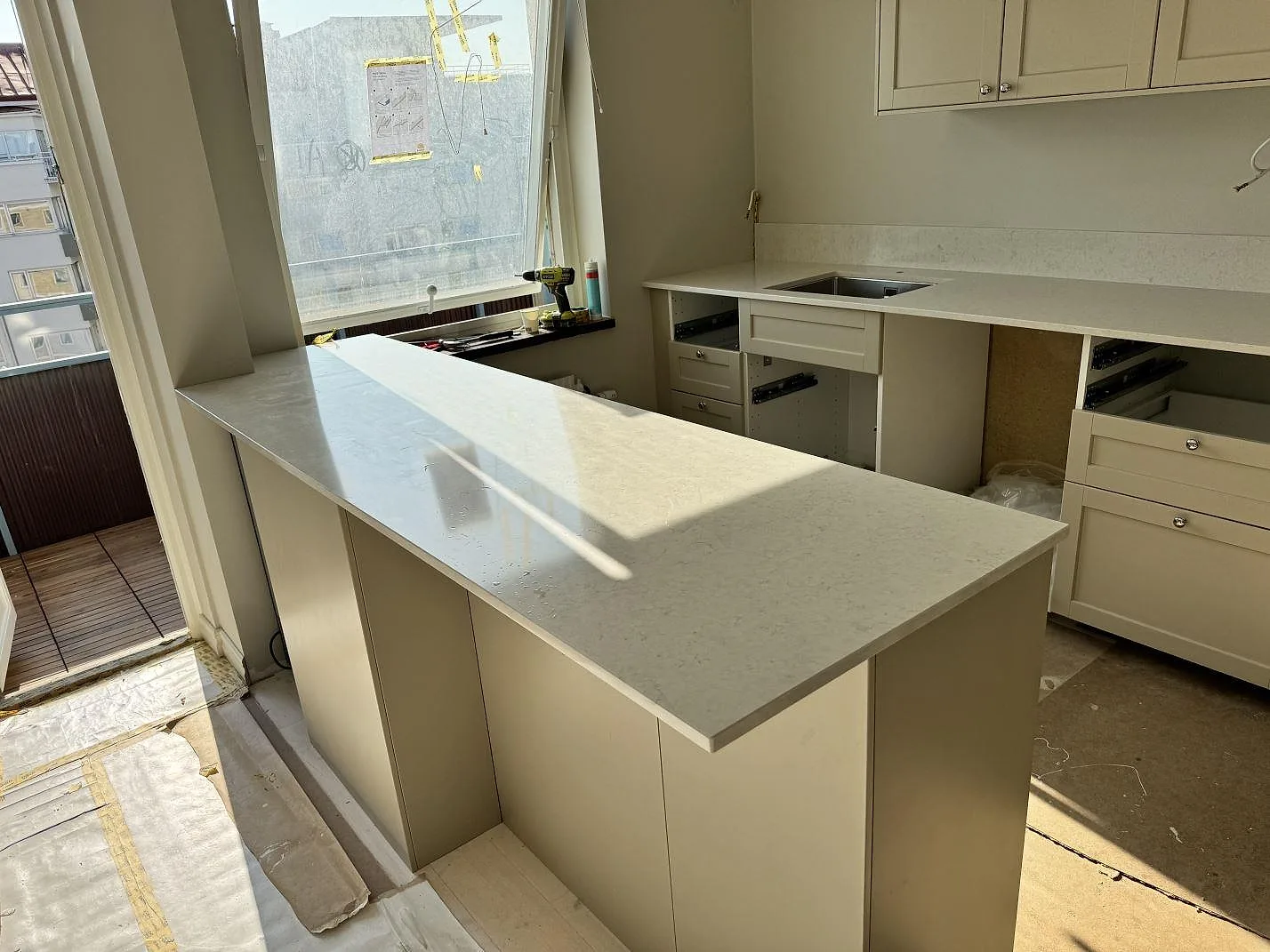 Köksbänkskiva i polerad Silestone Snowy Ibiza, ljus kvartskomposit, i ett lägenhetskök med burspråk i Malmö.