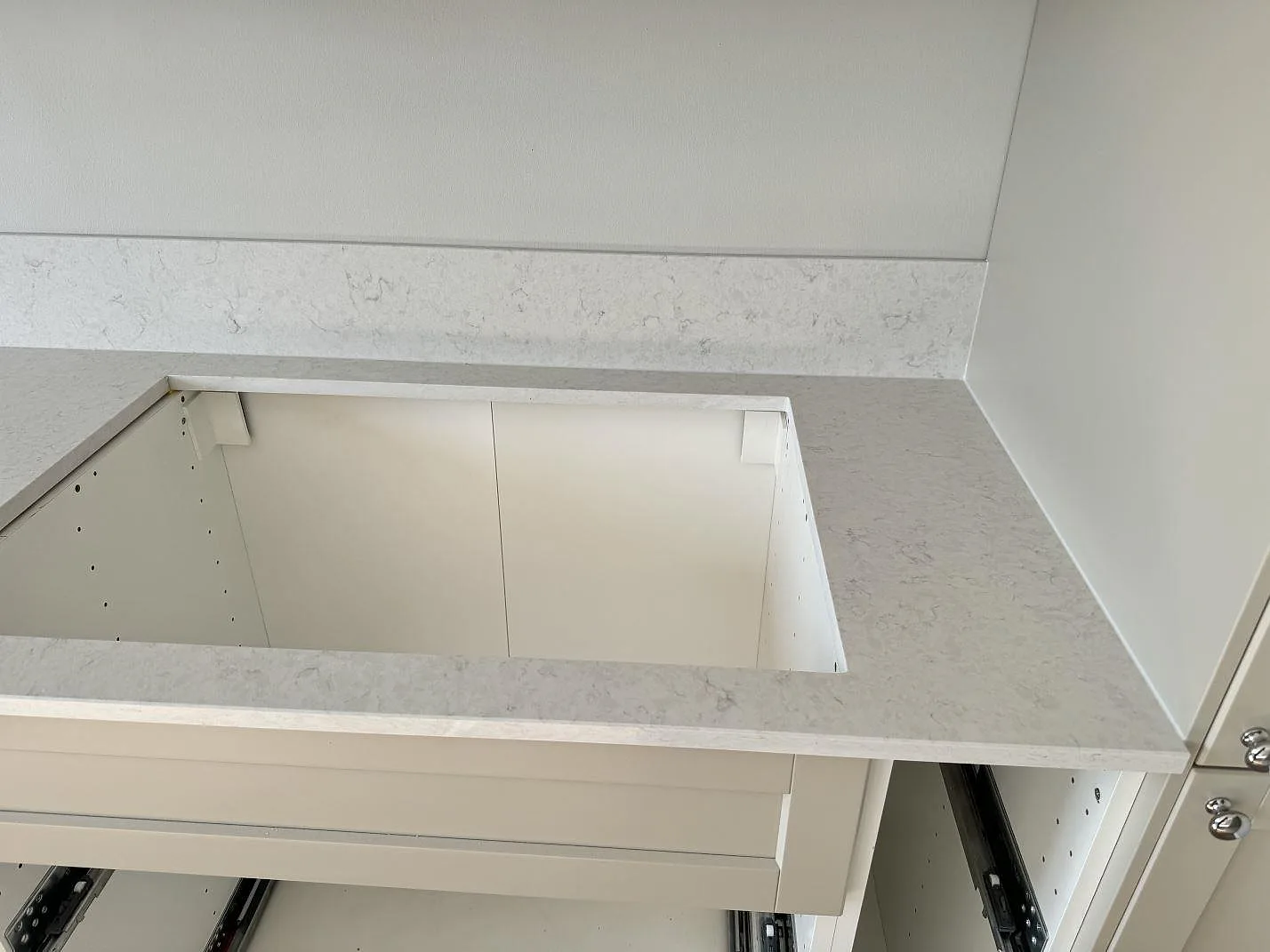 Närbild av polerad Silestone Snowy Ibiza runt diskhoöppning och låg stänkkant i ett kök under montering i Malmö.