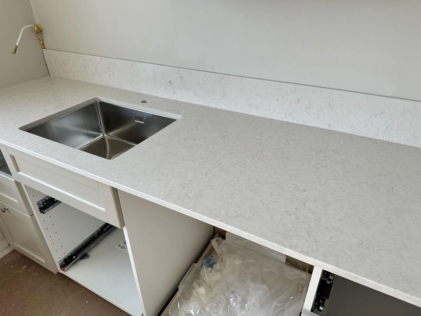 Polerad köksbänkskiva i Silestone Snowy Ibiza med rostfri diskho, låg stänkkant och ljus kvartskomposit i Malmö.