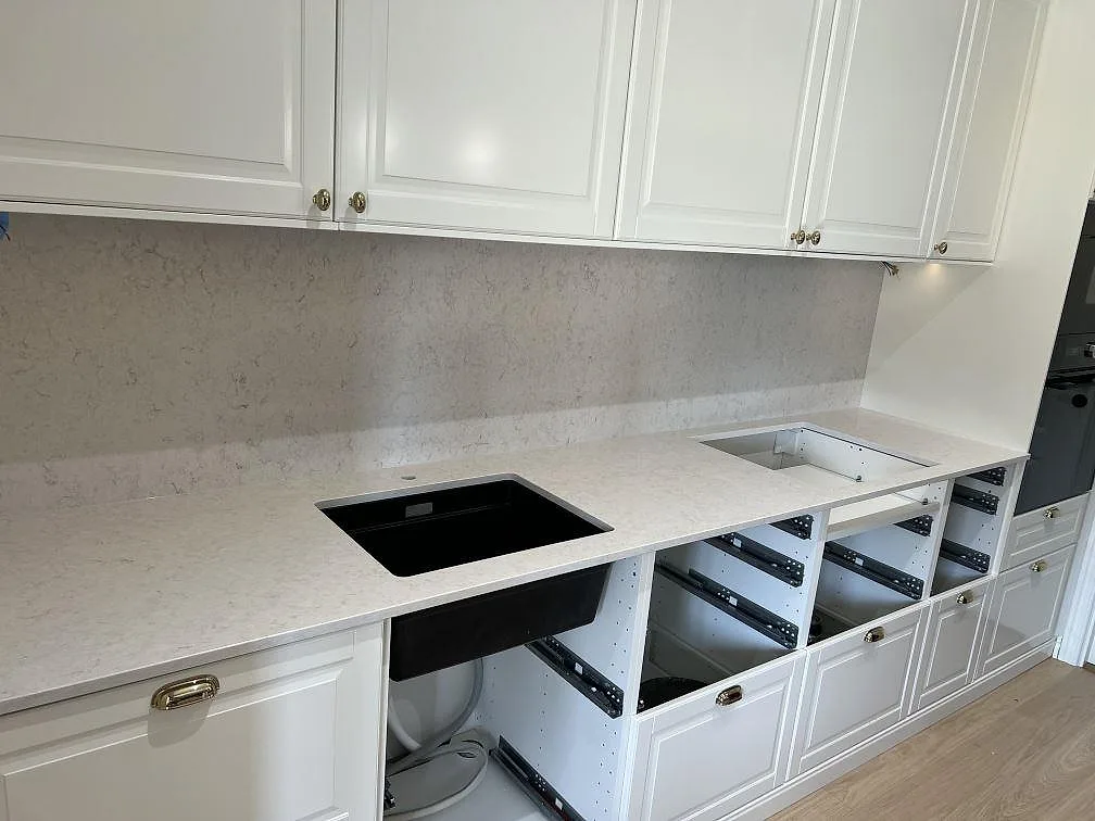 Lång köksbänkskiva i polerad Silestone Snowy Ibiza med underlimmad svart diskho, hällöppning och matchande stänkskydd i Malmö.
