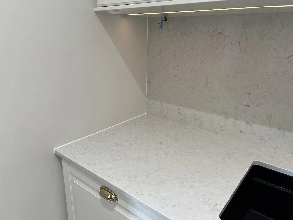 Vänster arbetsyta i polerad Silestone Snowy Ibiza med ljus ådring, underlimmad diskho och stänkskydd i Malmö.