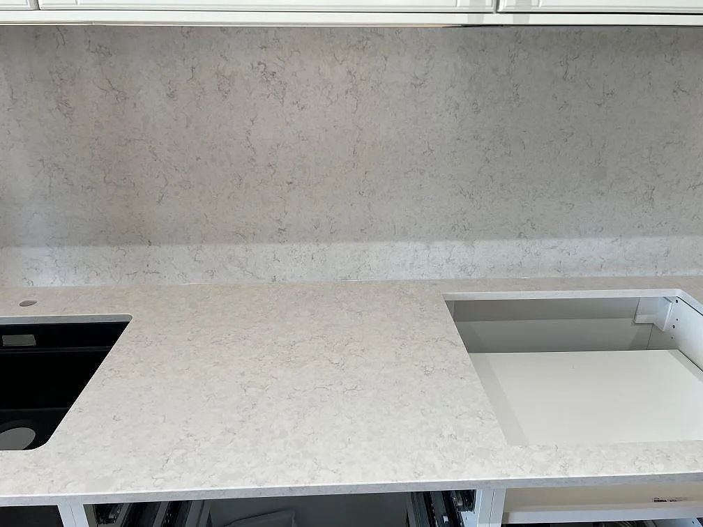 Polerad Silestone Snowy Ibiza bänkskiva med diskho till vänster, hällöppning och ljus ådring framför stänkskyddet i Malmö.