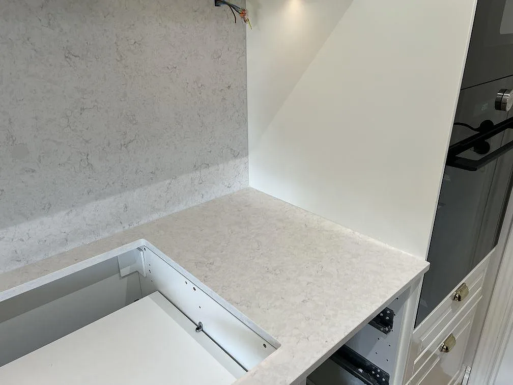 Höger del av köksbänkskivan i Silestone Snowy Ibiza, polerad, med hällöppning, stänkskydd och högskåp i Malmö.