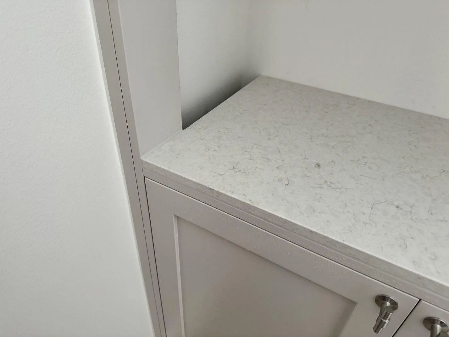 Detalj av polerad Silestone Snowy Ibiza på en kort väggbänk i MALMÖ, med vit lucka och ljus vägg runt stenen.