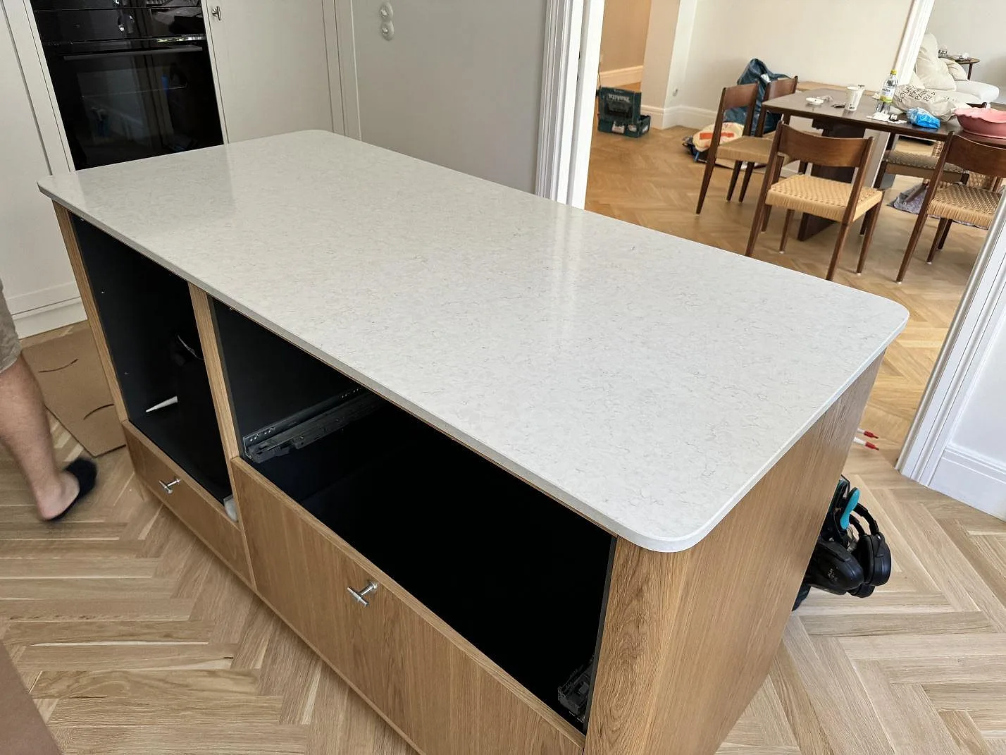Stor köksö med polerad köksbänkskiva i vit Silestone Snowy Ibiza i ett ljust kök i MALMÖ, med ljus träinredning och fiskbensgolv.