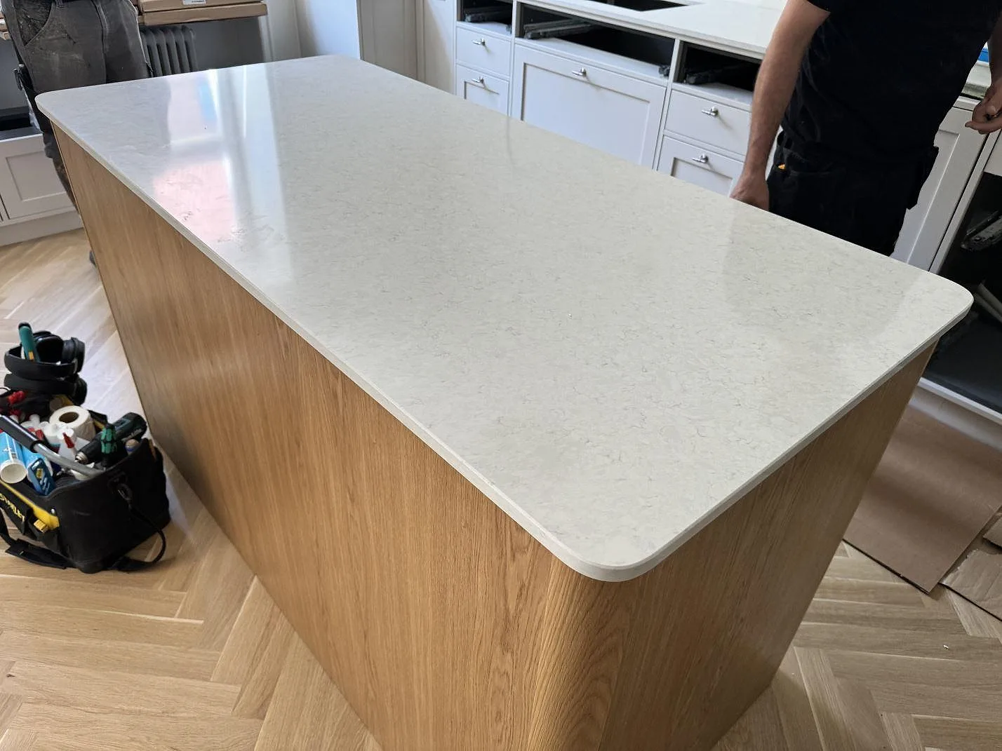 Närbild på den blanka köksön i Silestone Snowy Ibiza, polerad vit kvartskomposit på ljus träö i MALMÖ.