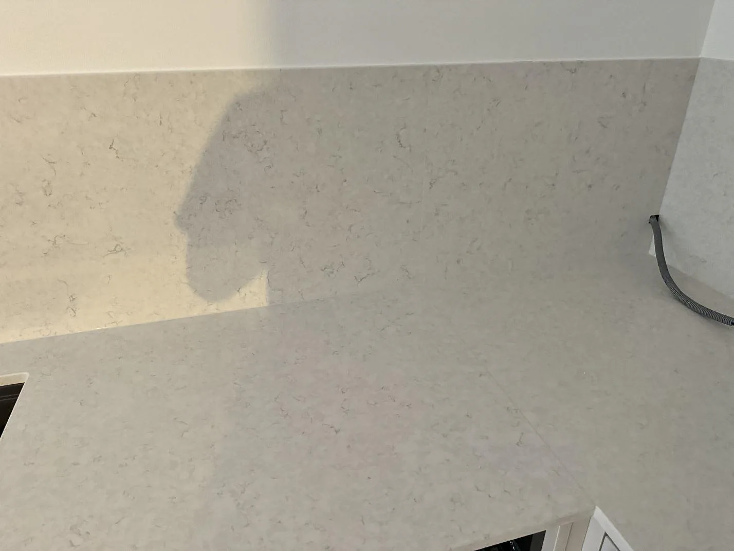 Närbild av stänkskydd och bänkskiva i polerad vit Silestone Snowy Ibiza i köksnisch i MALMÖ.