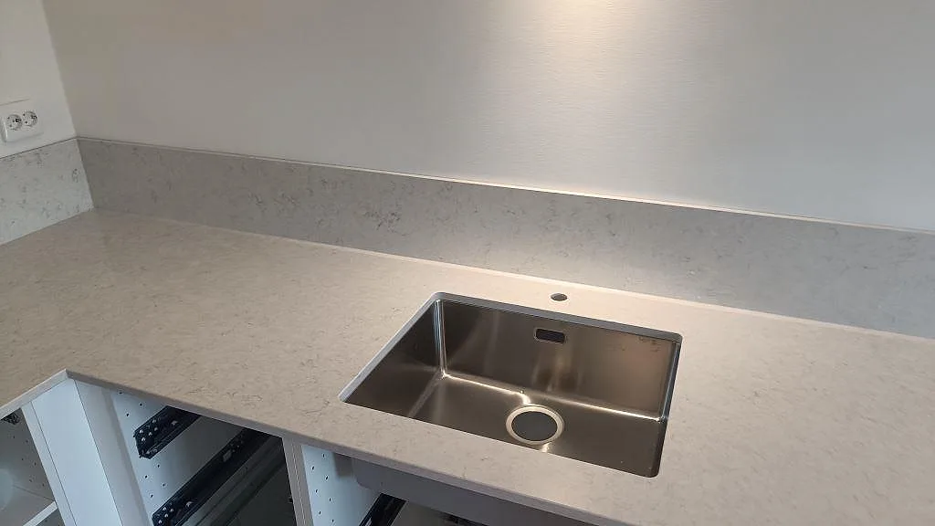 Närbild av polerad Silestone Snowy Ibiza som köksbänkskiva med underlimmad rostfri diskho och låg stänkkant i Malmö.
