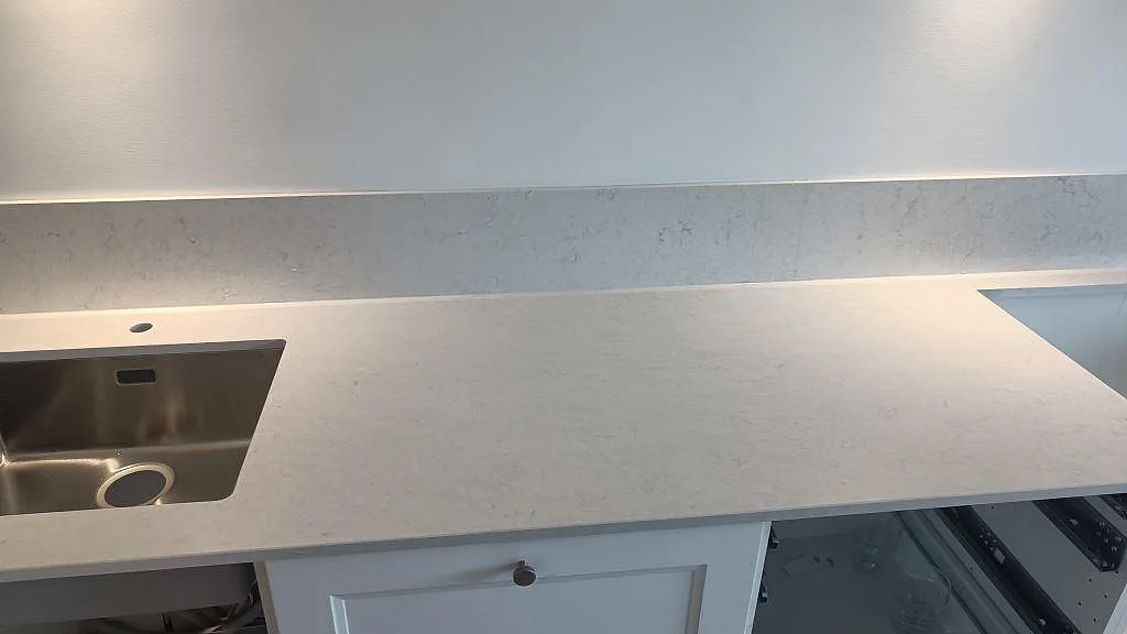 Polerad Silestone Snowy Ibiza över vita köksstommar med rostfri diskho, blandarhål och öppning för häll i Malmö.