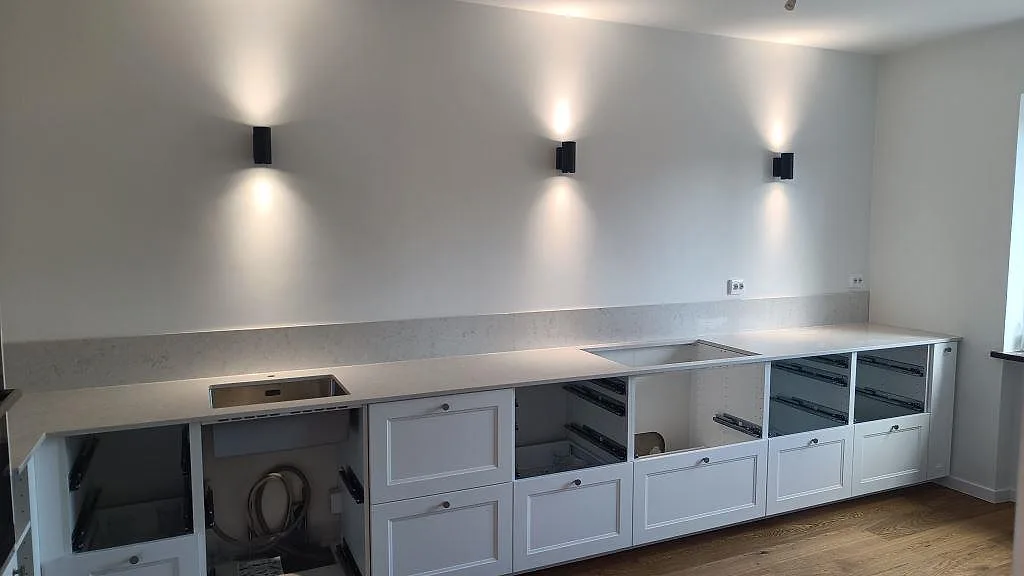 Polerad köksbänkskiva i Silestone Snowy Ibiza, vit kvartskomposit med låg stänkkant, rostfri underlimmad diskho och hällurtag i Malmö.