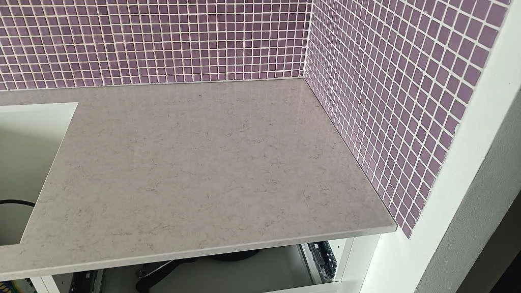 Hörnsektion av polerad Silestone Snowy Ibiza köksbänkskiva med ljus ådring och lila mosaikvägg i Malmö.