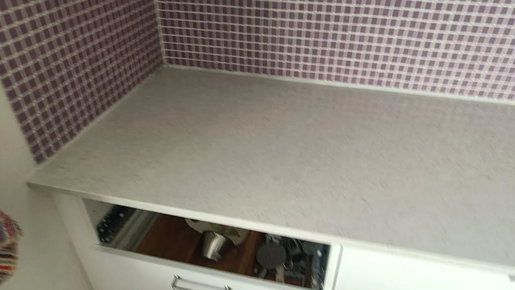 Detalj av ljus polerad Silestone Snowy Ibiza bänkskiva i kökshörn med vita stommar och mosaik i Malmö.