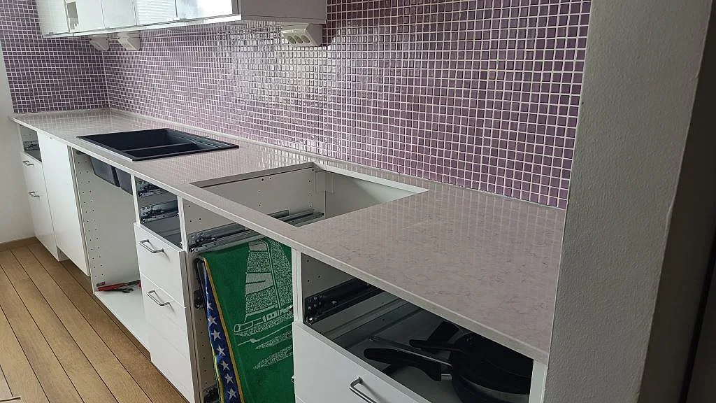 Polerad köksbänkskiva i Silestone Snowy Ibiza, 20 mm kvartskomposit, med svart diskho och öppen utskärning i ett kök i Malmö.