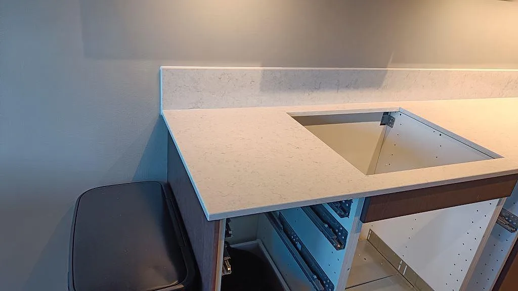 Polerad Silestone Snowy Ibiza som ljus köksbänkskiva med rektangulärt urtag och låg stänkkant i ett kök i Malmö.