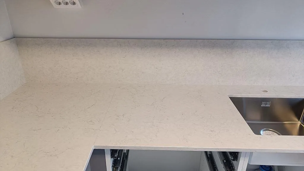 Arbetsyta i polerad Silestone Snowy Ibiza med diskho till höger och matchande stänkskydd längs väggen i ett kök i Malmö.