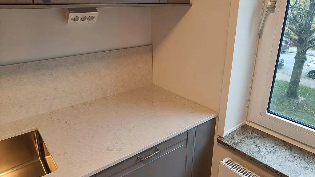 Bänkskiva i polerad Silestone Snowy Ibiza vid diskho och fönster, med matchande stänkskydd i ett kök i Malmö.