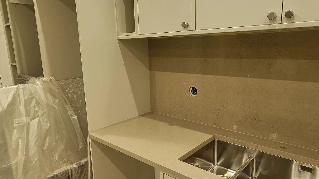 Hörn vid diskho med polerad Silestone Snowy Ibiza, rostfri diskho och väggbeklädnad i Silestone Coral Clay i Malmö.