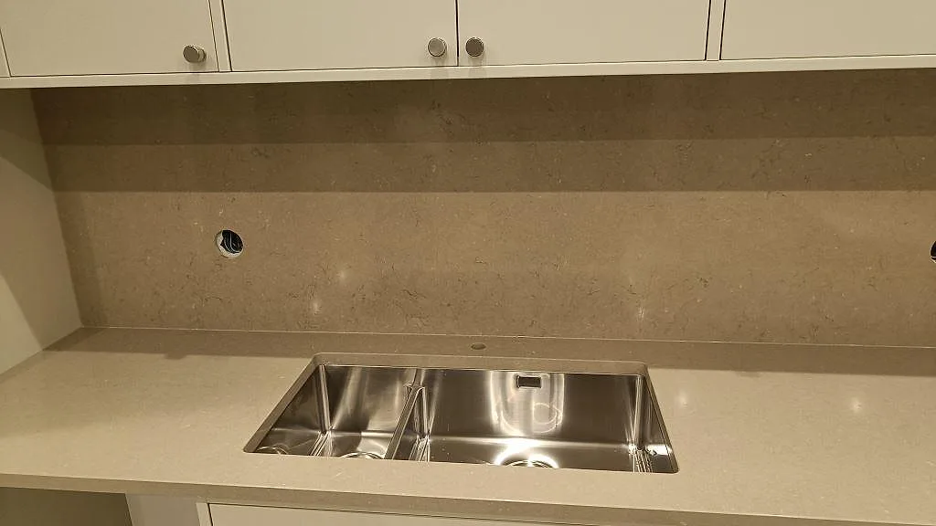 Diskhozon med polerad Silestone Snowy Ibiza, rostfri diskho och varm Silestone Coral Clay som stänkskydd i Malmö.