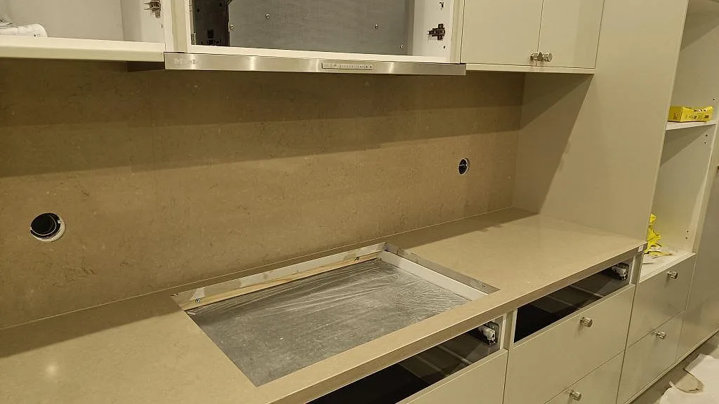 Rak köksbänk i polerad Silestone Snowy Ibiza med hälluttag och hög väggbeklädnad i Silestone Coral Clay i Malmö.