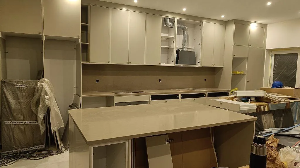 Polerad köksbänkskiva i Silestone Snowy Ibiza med stor arbetsö framför en rak bänkrad under montering i Malmö.