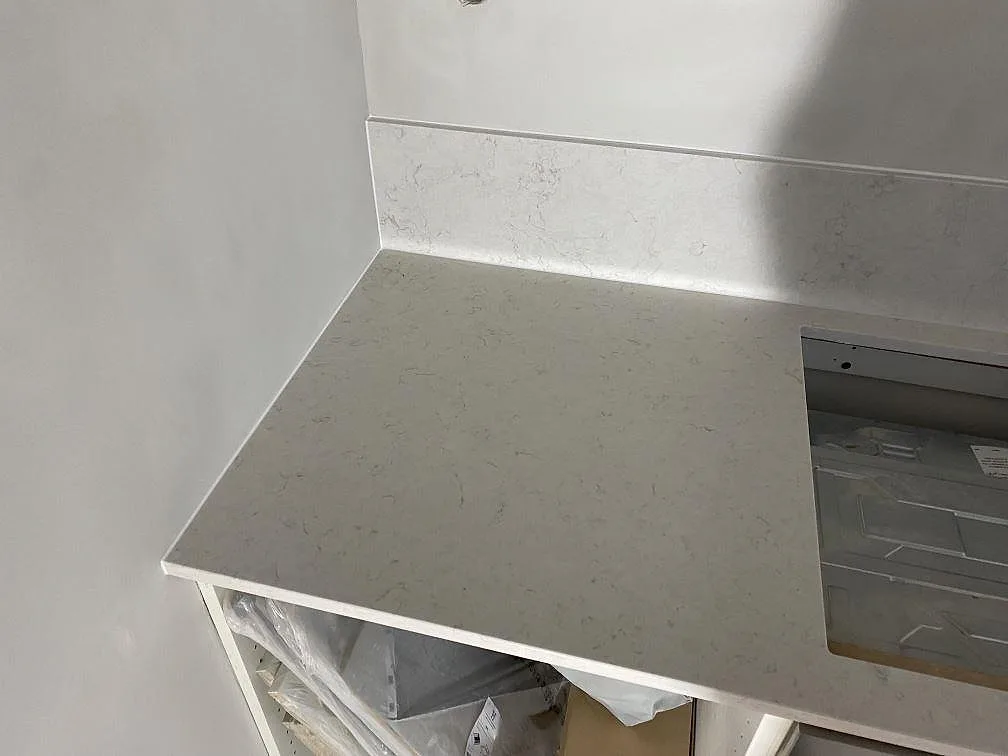 Vänster arbetsyta i Silestone Snowy Ibiza, polerad kvartskomposit, med hällöppning och lågt stänkskydd i Malmö.