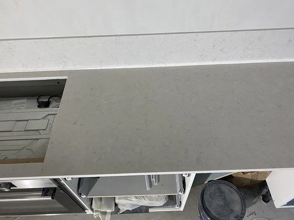 Detalj av polerad Silestone Snowy Ibiza på köksbänk med hälluttag, diskret grå ådring och stänkskydd i Malmö.
