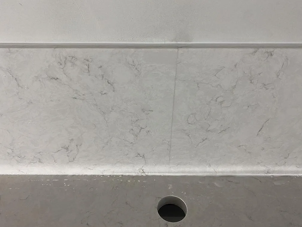 Närbild på stänkskydd och bänkyta i polerad Silestone Snowy Ibiza med borrat hål bakom diskhon i Malmö.