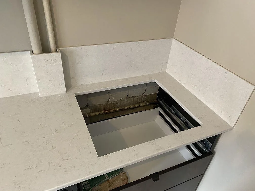 Hällöppning i polerad Silestone Snowy Ibiza med uppvikta stänkskydd längs väggarna i ett kök i Malmö.