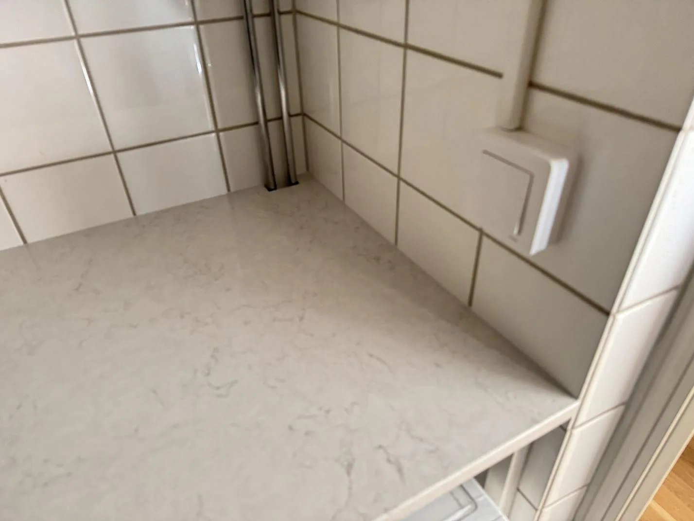 Närbild på polerad Silestone Snowy Ibiza i en kaklad nisch med synlig ljus ådring i Malmö.
