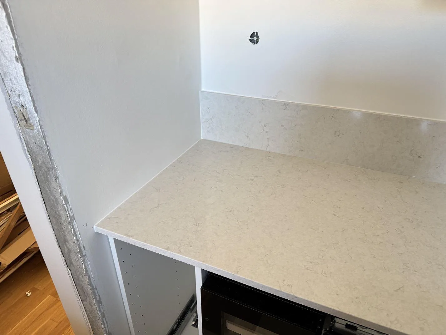 Polerad Silestone Snowy Ibiza som bänkskiva och uppvikt stänkkant i ett kök under montering i Malmö.