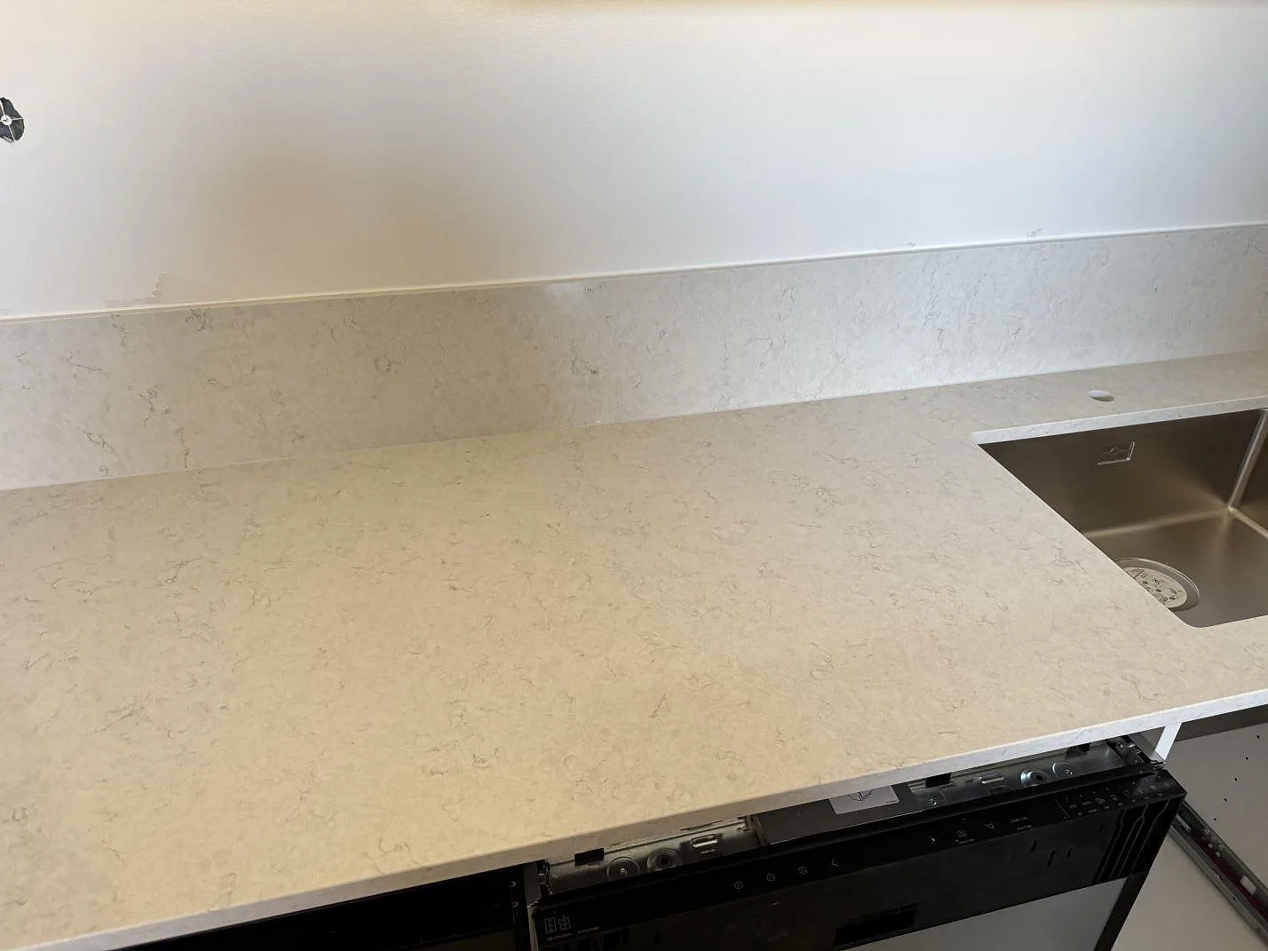 Köksbänkskiva i polerad Silestone Snowy Ibiza med låg stänkkant och rostfri diskho i ett kök i Malmö.