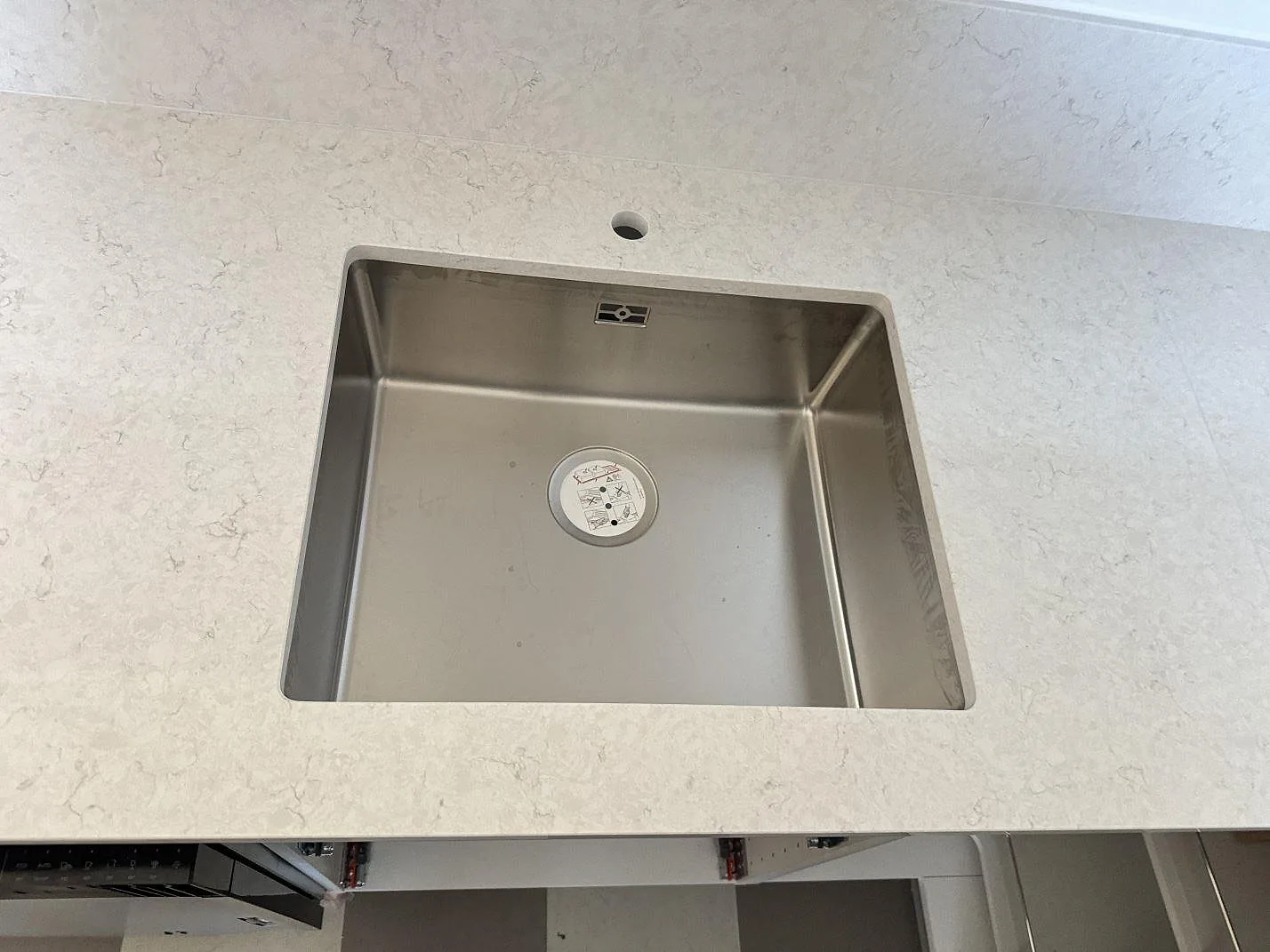 Detalj av polerad Silestone Snowy Ibiza runt en rostfri diskho med rund blandaröppning i Malmö.