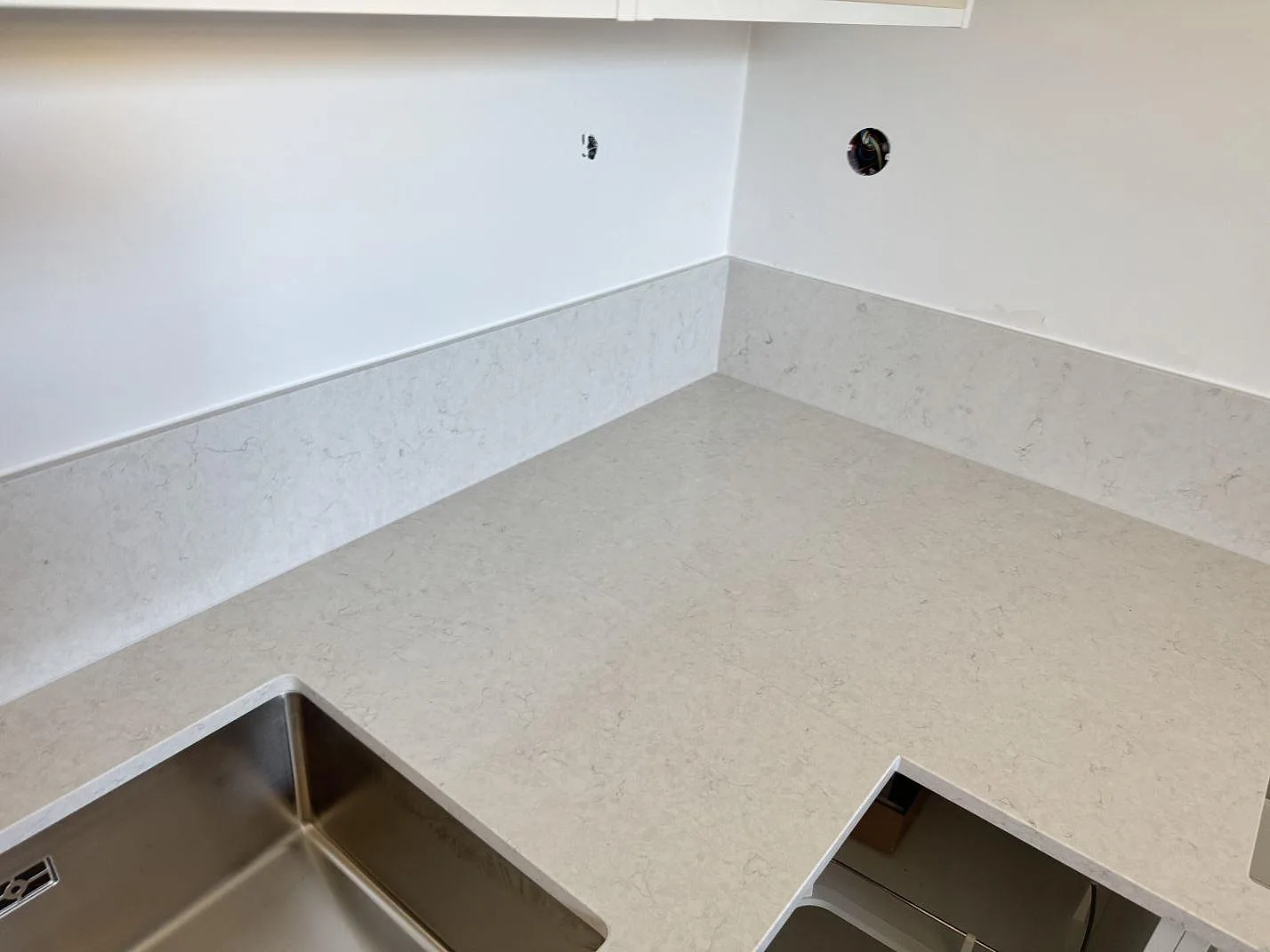 L-formad köksbänk i polerad Silestone Snowy Ibiza med stänkskydd och öppningar för köksutrustning i Malmö.