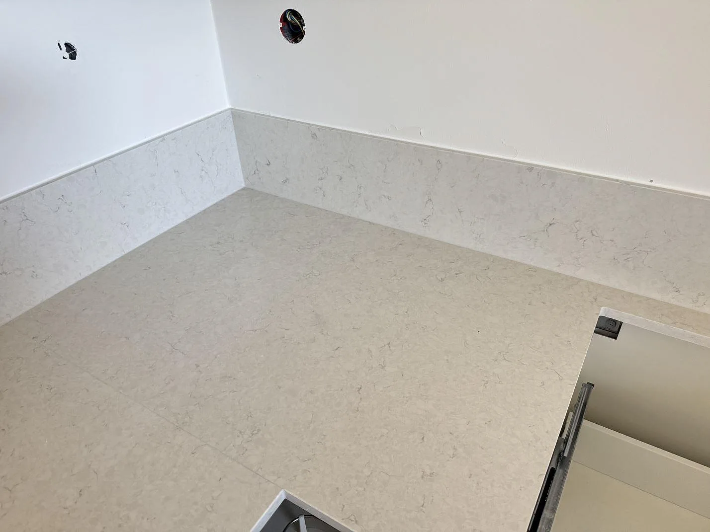Närbild på den ljusa ådringen i polerad Silestone Snowy Ibiza över köksstommar i Malmö.