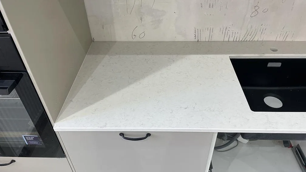 Närbild av polerad Silestone Snowy Ibiza i vit komposit med svart diskho och uppvikt stänkkant i ett kök i Malmö.