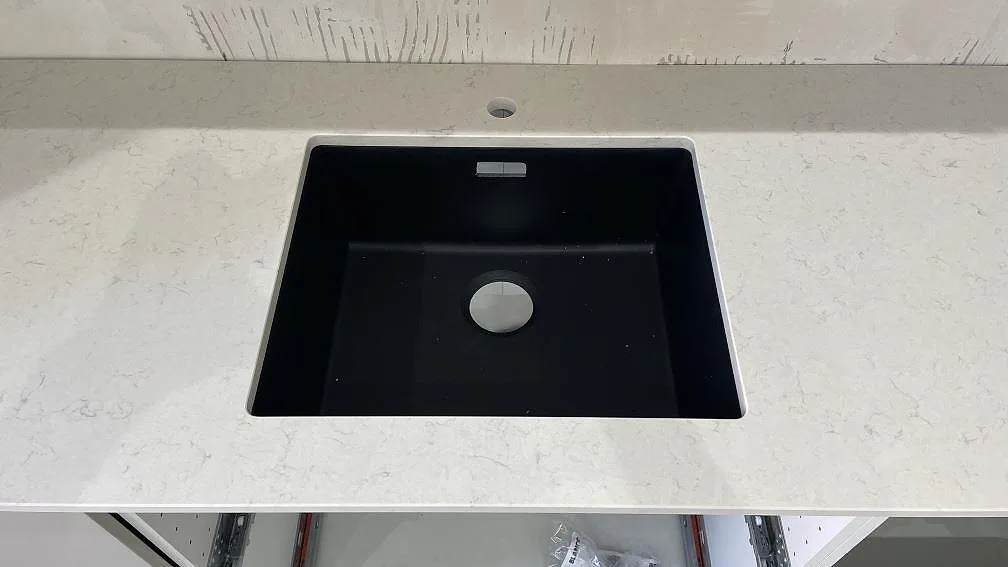Detaljbild av svart diskho i polerad Silestone Snowy Ibiza, vit kompositbänkskiva med diskret ådring i Malmö.