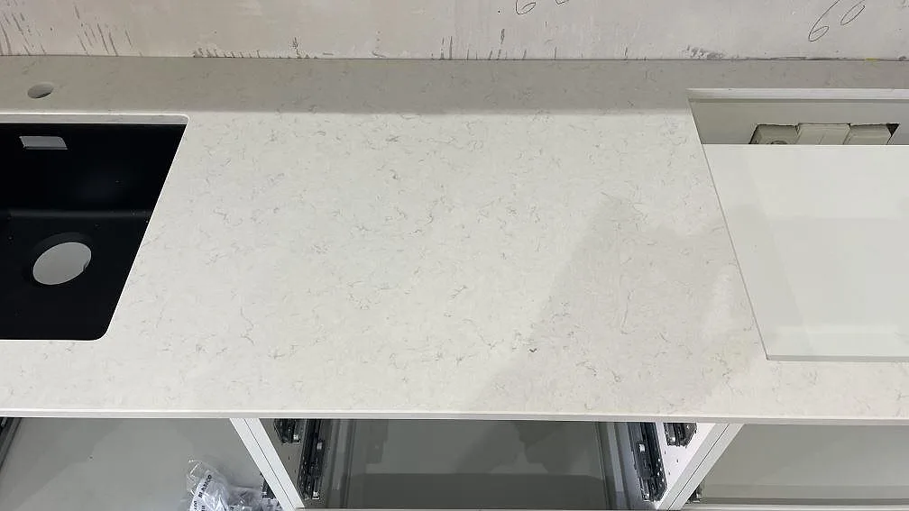 Polerad Silestone Snowy Ibiza i vit komposit med svart diskho, hällurtag och låg stänkkant under montering i Malmö.
