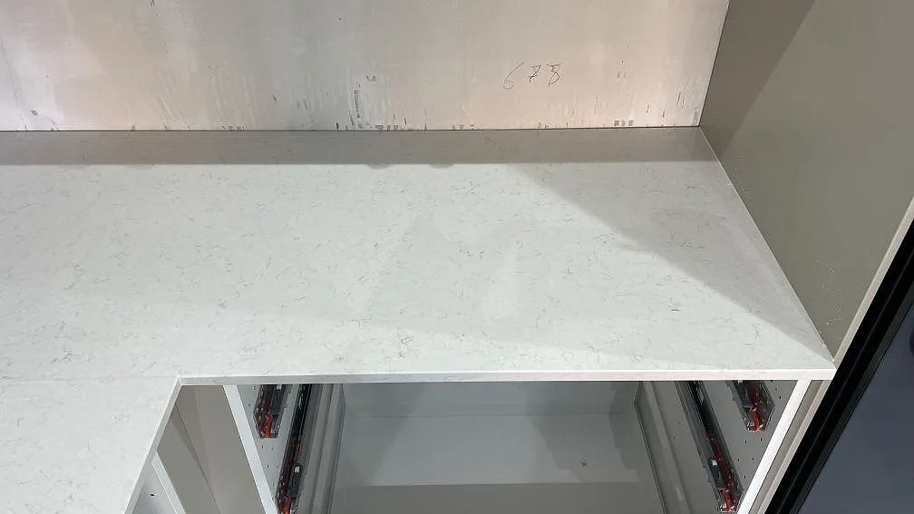 Höger bänkyta i polerad Silestone Snowy Ibiza, vit kvartskomposit med diskret ådring och uppvikt stänkkant i Malmö.