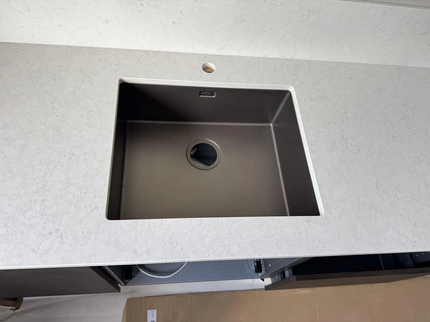 Detalj av polerad Silestone Snowy Ibiza runt en underlimmad rostfri diskho med blandarhål i ett kök i Malmö.