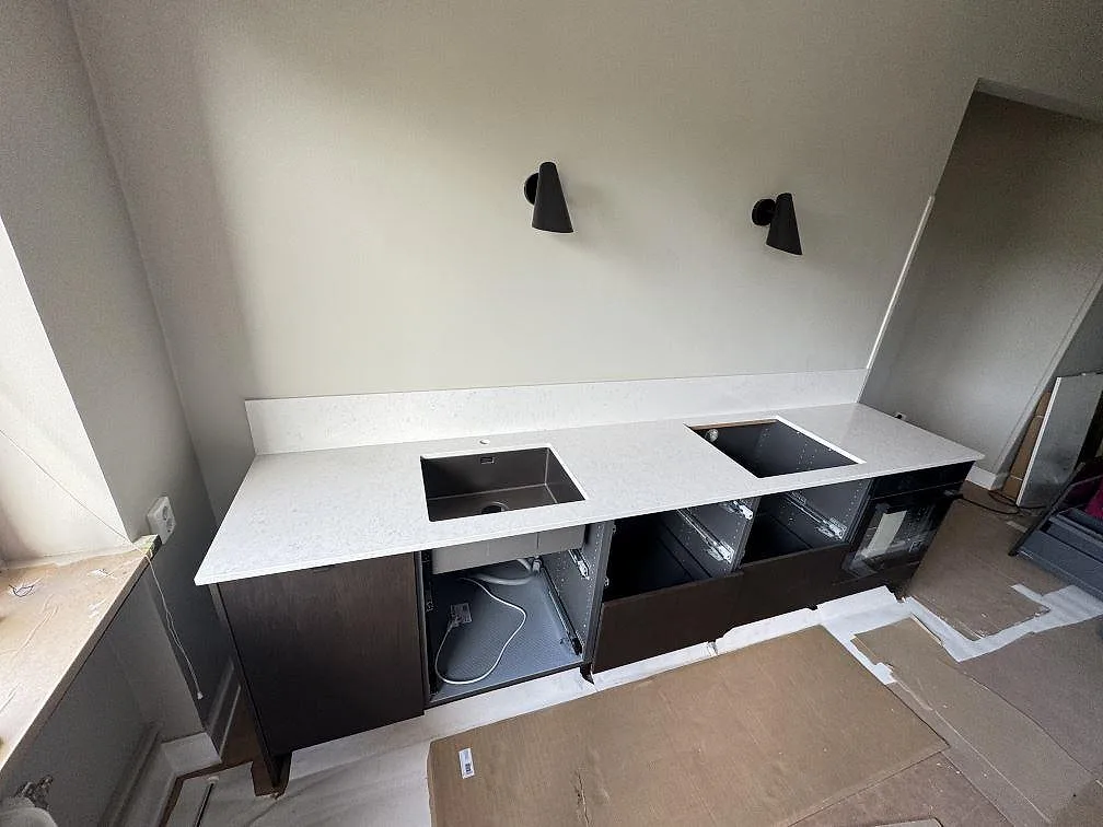 Rak köksbänkskiva i polerad Silestone Snowy Ibiza med rostfri diskho, rektangulär öppning och lågt stänkskydd i ett kök i Malmö.