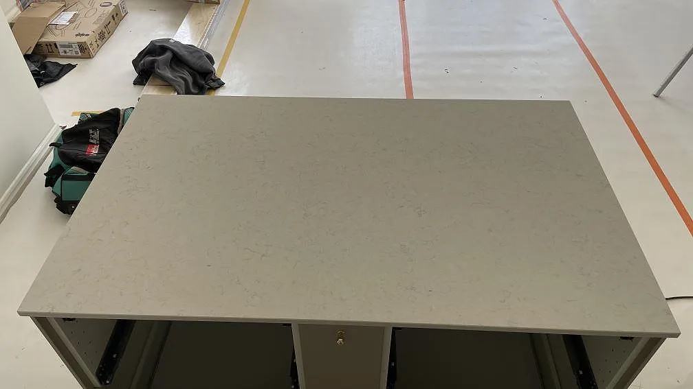 Närbild ovanifrån på köksön i polerad Silestone Snowy Ibiza, vit kvartskomposit med diskret grå ådring, i ett kök under montering i Malmö.
