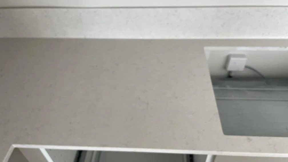 Detalj av polerad Silestone Snowy Ibiza runt ett rektangulärt förberett urtag, vit kvartskomposit och stänkkant i köket i Malmö.