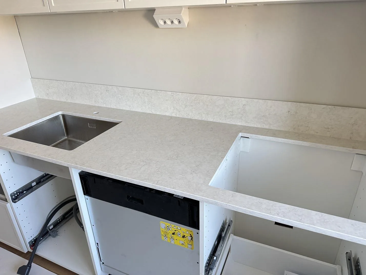 Väggbänk i 20 mm polerad Silestone Snowy Ibiza med rostfri diskho, hälluttag och lågt stänkskydd i Malmö.
