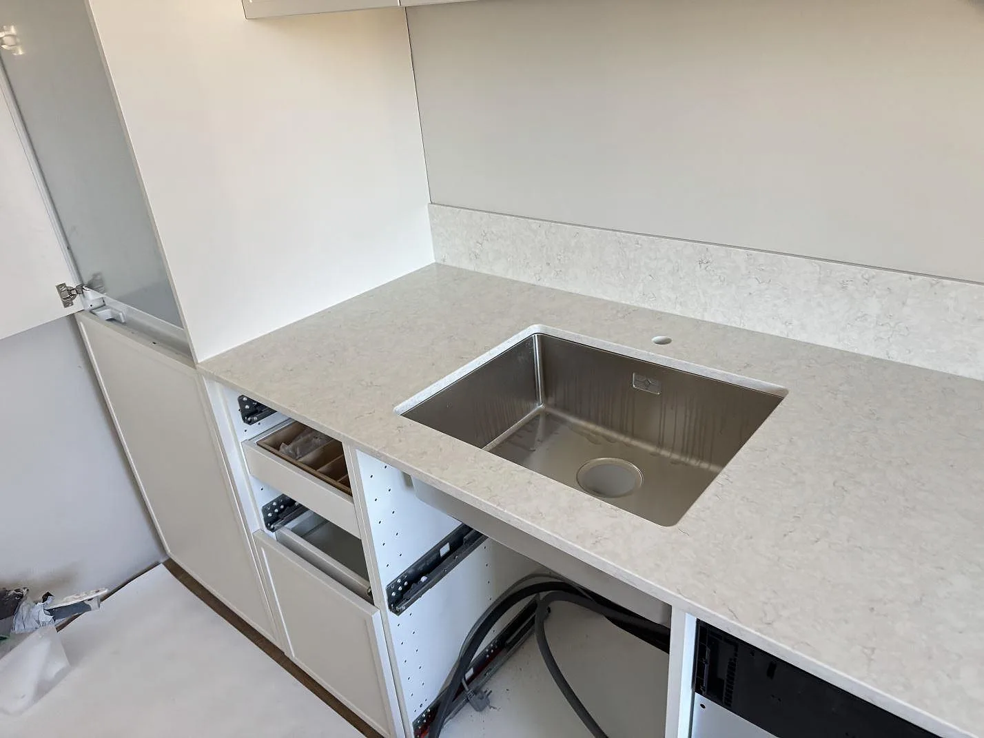 Diskzon med underlimmad rostfri diskho i polerad Silestone Snowy Ibiza och matchande stänkskydd i ett kök i Malmö.