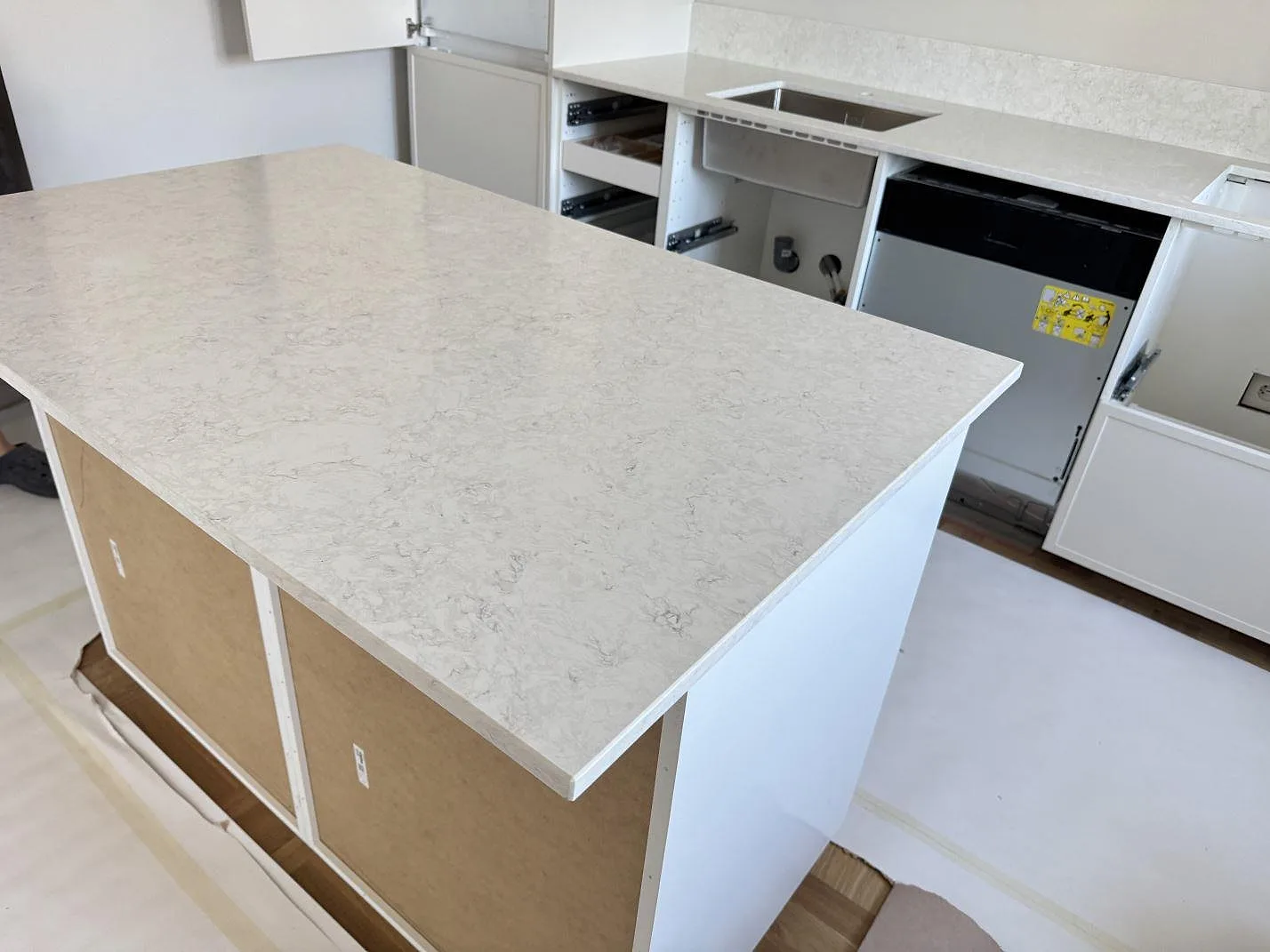 Köksö med polerad Silestone Snowy Ibiza i kvartskomposit, monterad framför väggbänk med underlimmad rostfri diskho i Malmö.