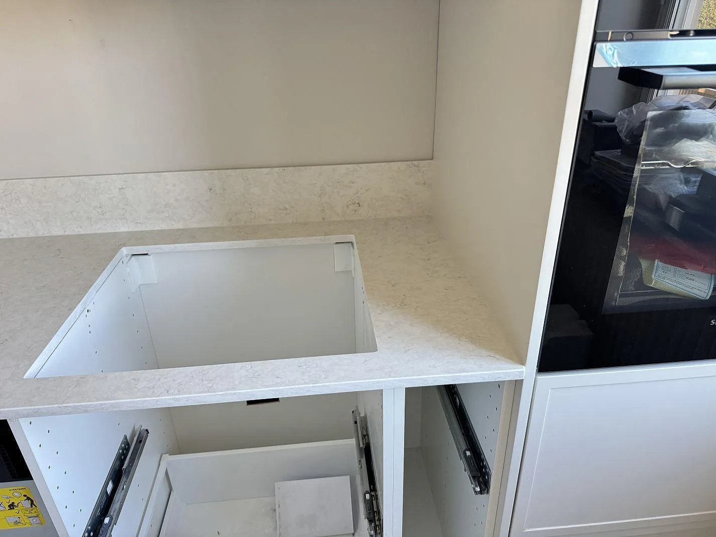 Polerad Silestone Snowy Ibiza runt ett hälluttag med lågt stänkskydd och inbyggd ugn vid köksväggen i Malmö.